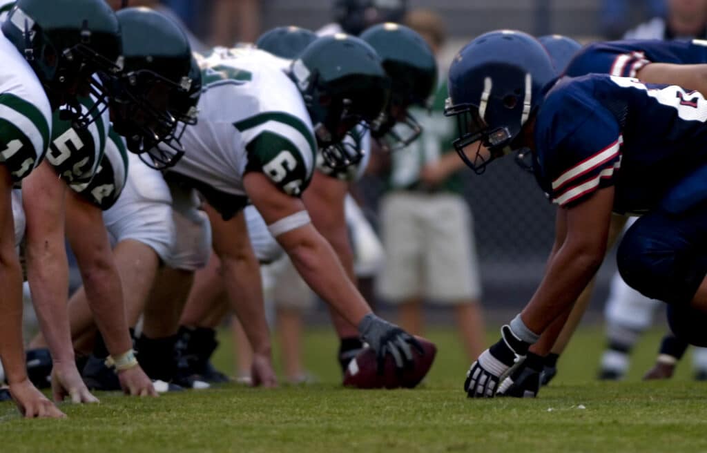 Football players wearing helmets lined up at the line of scrimmage.