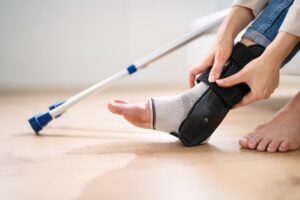 Person holding injured ankle in brace after workplace injury.