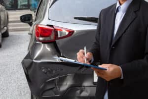 A man in a suit filling out paperwork after a work-related car accident