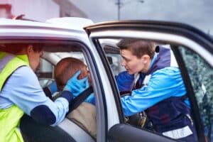 Paramedics tending to a car accident victim after a seat belt failure