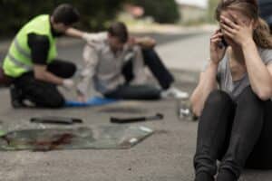 A woman sitting on the ground after a car accident