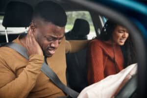 Driver and passenger experiencing pain inside a car after airbag deployment.